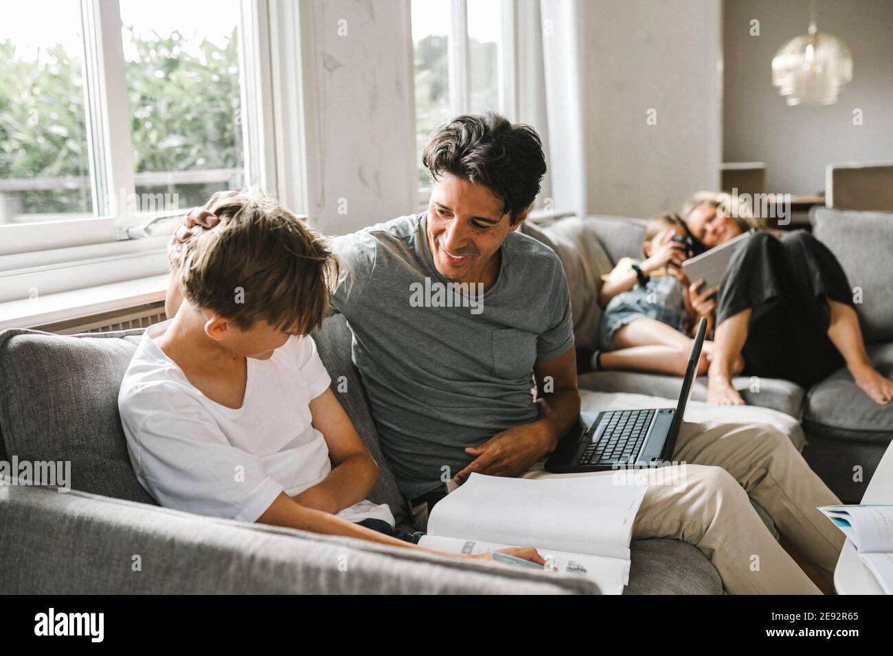 Glücklicher Vater mit Sohn macht seine Hausaufgaben zu Hause Stockfoto