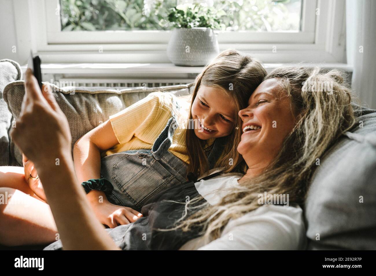 Lächelnde Mutter und Tochter mit digitalem Tablet im Wohnzimmer Stockfoto