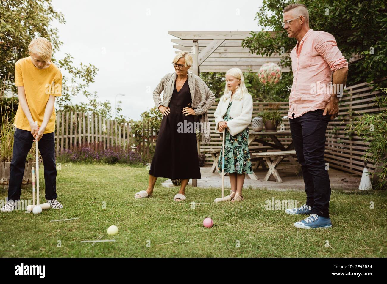 Pre-Jugendlicher Junge spielt Polo mit Familie im Hinterhof Stockfoto