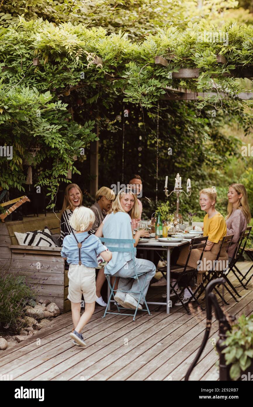 Lächelnde Familie, die den Jungen beim Abendessen ansieht Hinterhof Stockfoto