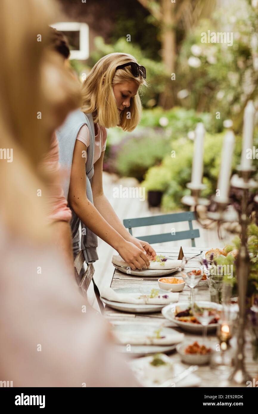 Teenager-Mädchen, die Teller auf dem Tisch für die Dinner-Party arrangieren Stockfoto