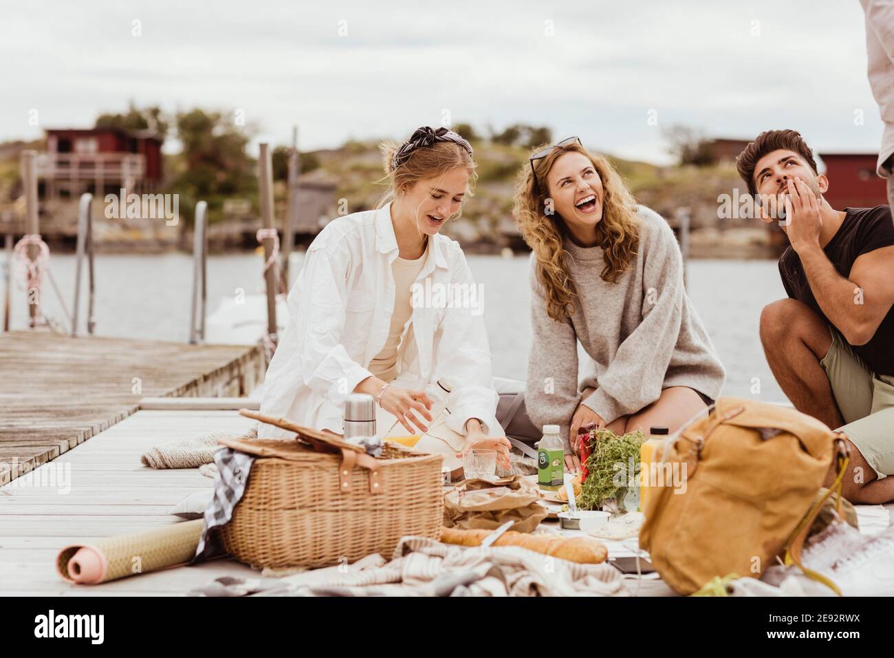 Freunde lachen beim Essen Snacks während Picknick am Hafen Stockfoto