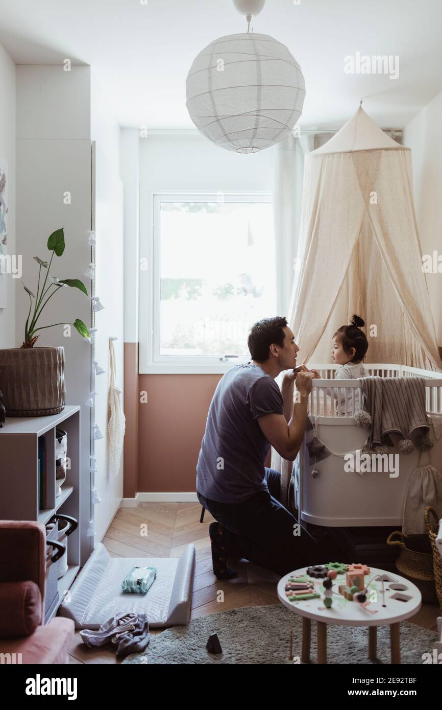 Vater spielt mit männlichen Kleinkind in Krippe zu Hause Stockfoto
