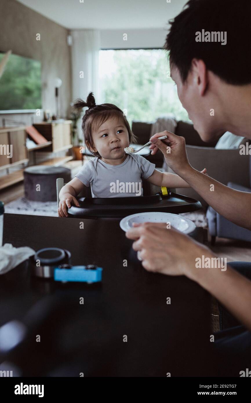 Zugeschnittenes Bild von Vater Fütterung Baby Sohn zu Hause Stockfoto