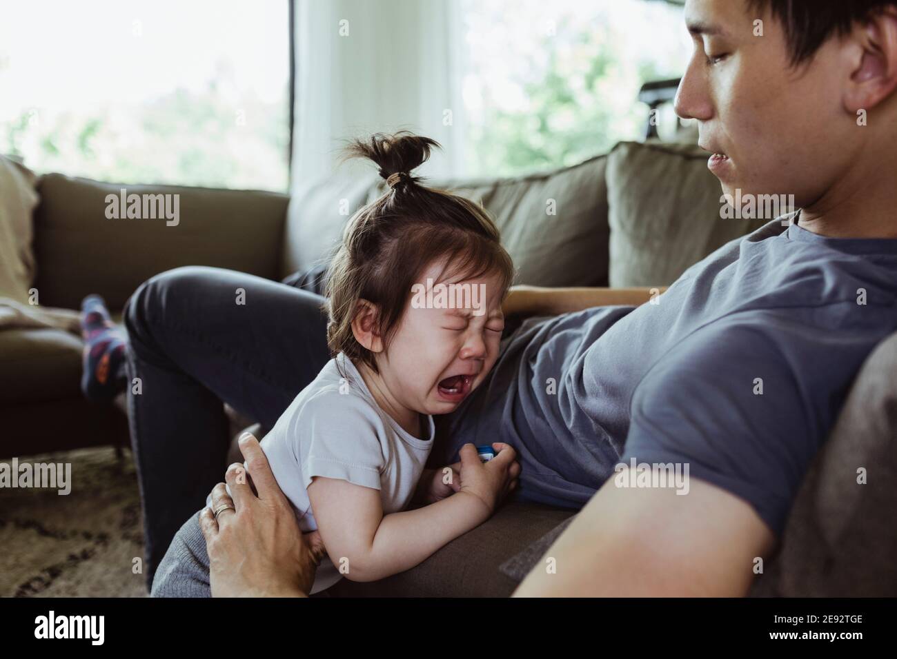 Vater auf Vaterschaft verlassen Blick auf männliche Kleinkind weinend in Wohnzimmer Stockfoto