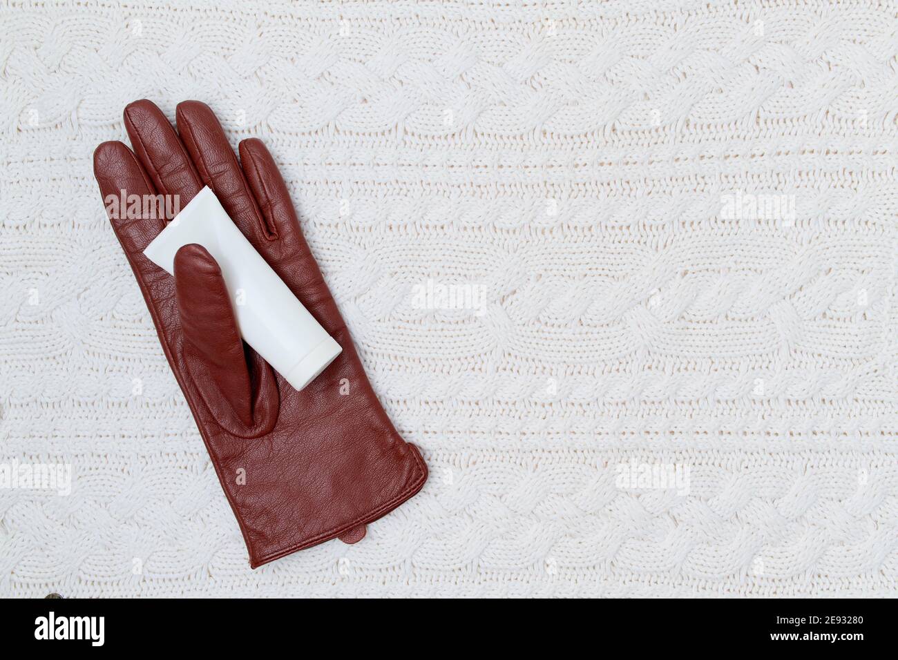 Winterflachlegen mit Handcreme und Handschuhen auf weißem Strickhintergrund. Stockfoto