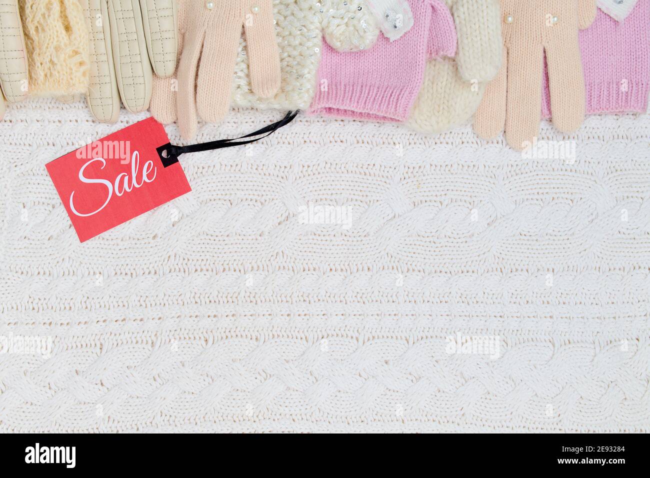 Winter flach Lay mit Fäustlingen, Handschuhe und Sale-Tag auf weißem gestrickten Hintergrund. Stockfoto