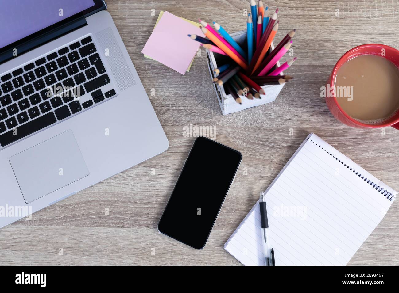 Arbeitsplatz Schreibtisch mit Smartphone Laptop Notebook Bleistifte und Tasse Kaffee Stockfoto