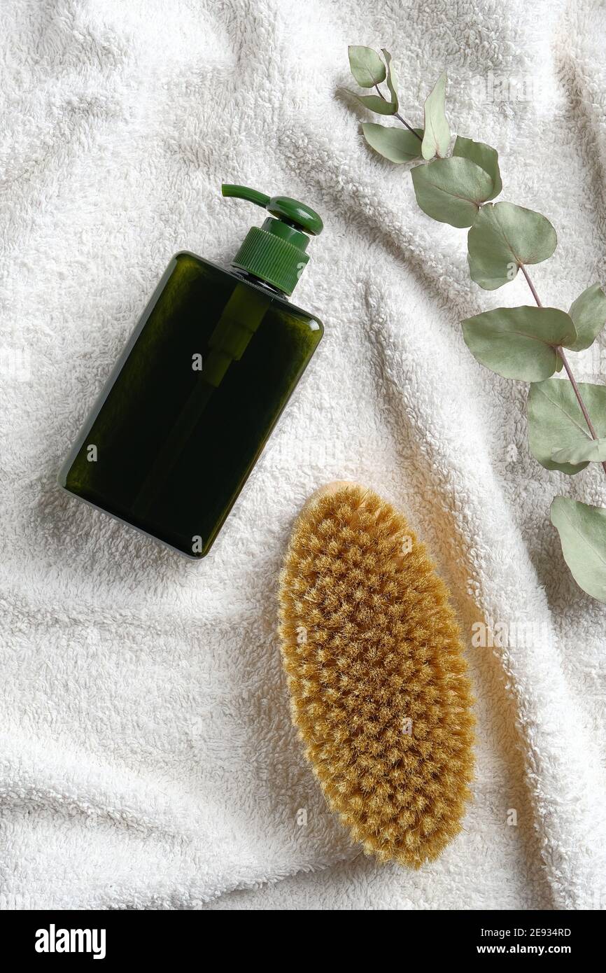 Trockene Bürste und Bio-Lotion Spender Flasche auf weißem Handtuch im Badezimmer. Körperpflege, Anti Aging, Anti Cellulite Massage Konzept. Flach liegend, Draufsicht. Stockfoto