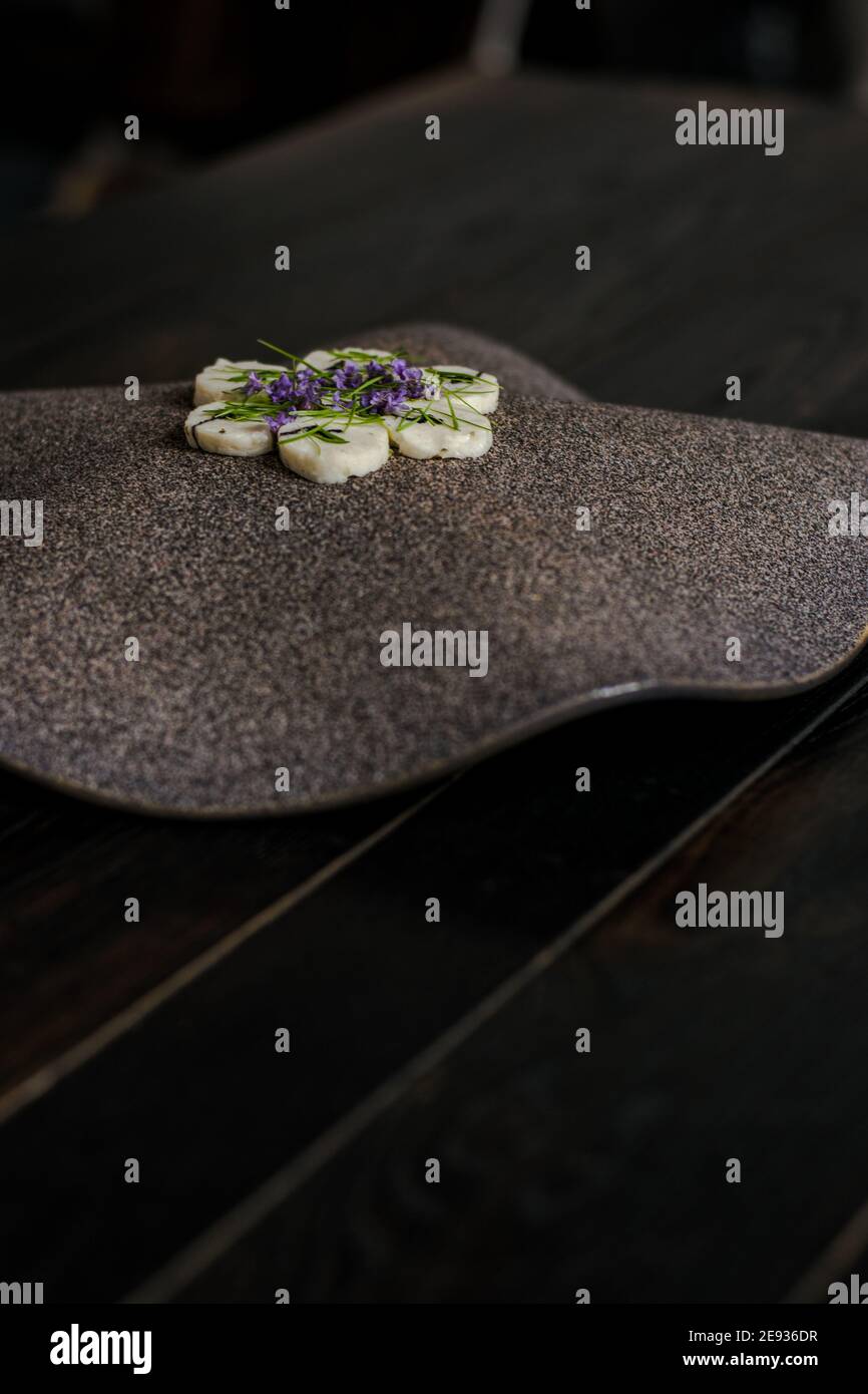 Fischroulade auf einem interessanten Teller, der mit Tannennadeln verziert ist In einem Restaurant Stockfoto