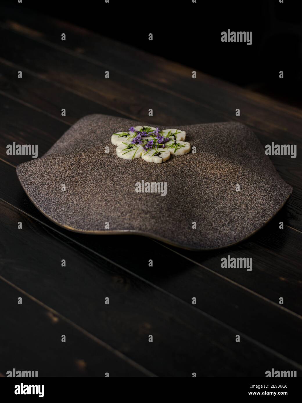 Fischroulade auf einem interessanten Teller, der mit Tannennadeln verziert ist In einem Restaurant Stockfoto