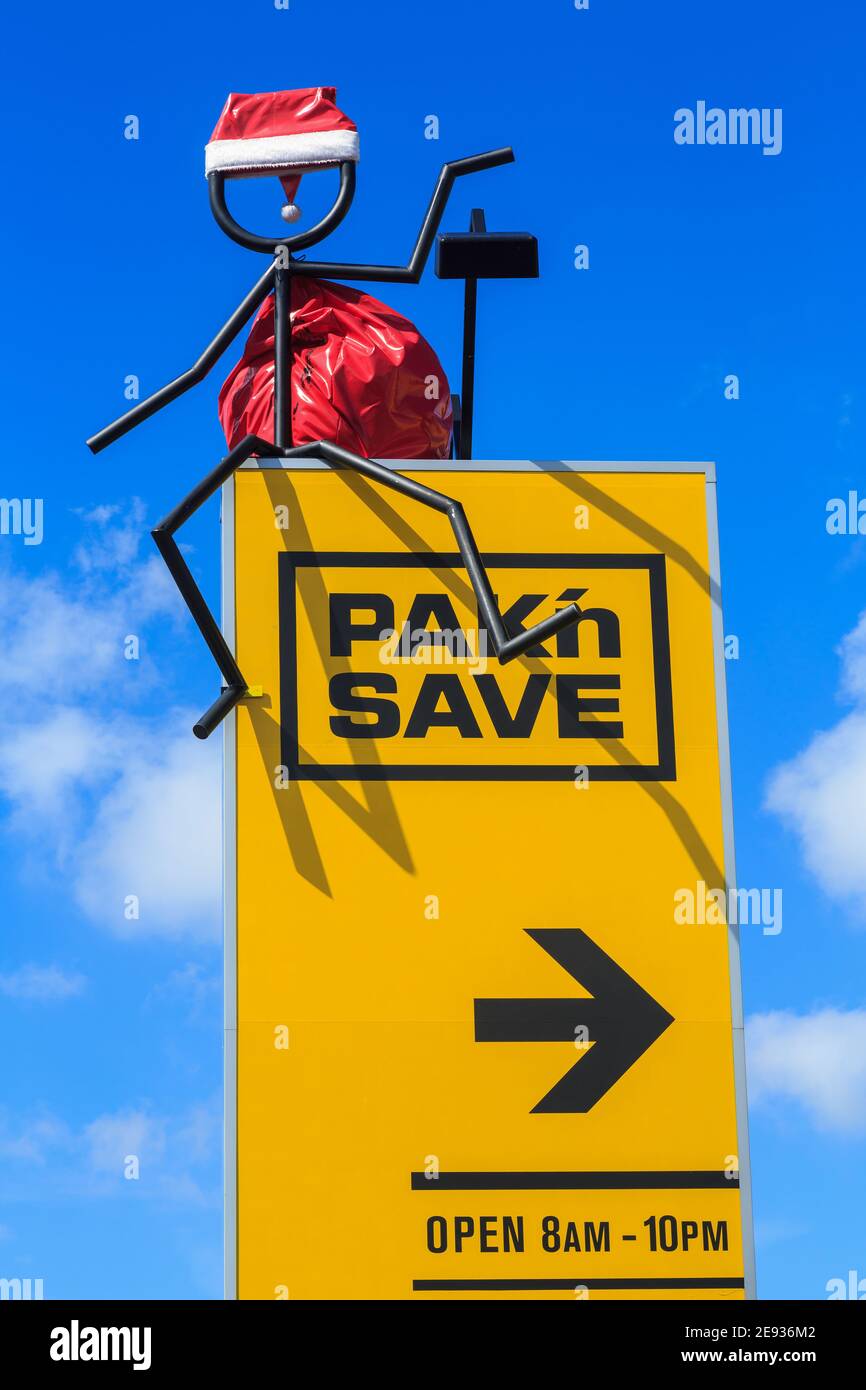 Ein Pak'nSave Supermarkt Schild in Neuseeland. Ihr "Stickman"-Maskottchen ist mit einem Weihnachtshut und einem Weihnachtssack geschmückt Stockfoto