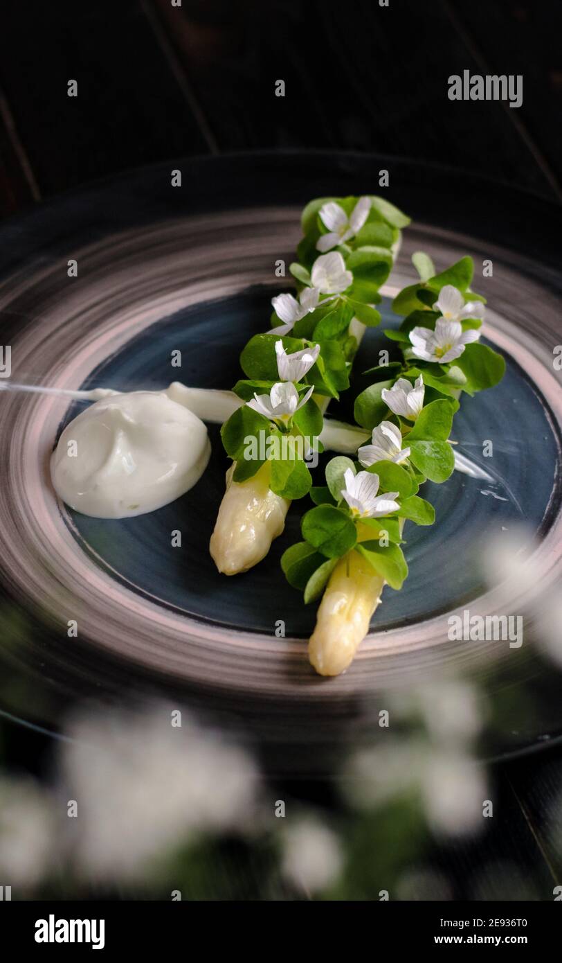 Gericht gekochten weißen Spargel plattiert und mit Weiß dekoriert Blumen und Sahne auf der Seite in einem Restaurant Stockfoto