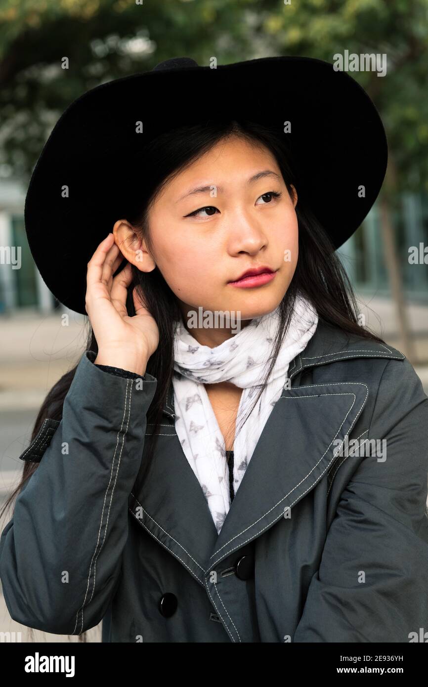 Vertikales Porträt einer schönen und eleganten jungen asiatischen Frau mit Hut, Konzept der Eleganz und städtischen Lebensstil Stockfoto