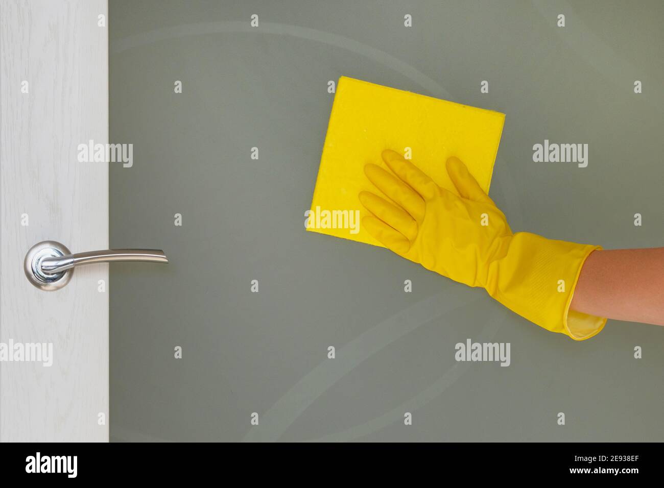 Reinigungskonzept zu Hause. Weibliche Hand mit gelbem Lappen wischt Glastür zu Hause. Hausarbeit und Housekeeping Konzept. Stockfoto