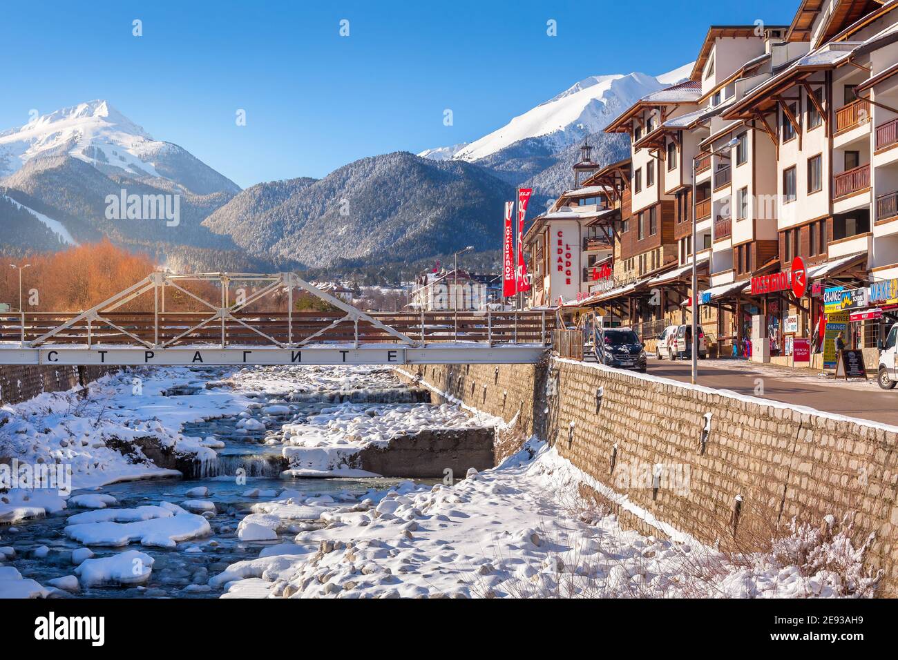 Bansko, Bulgarien - 28. Januar 2021: Fluss Glazne in der bulgarischen Stadt, Hotelhäuser und Schnee Pirin Berge Stockfoto