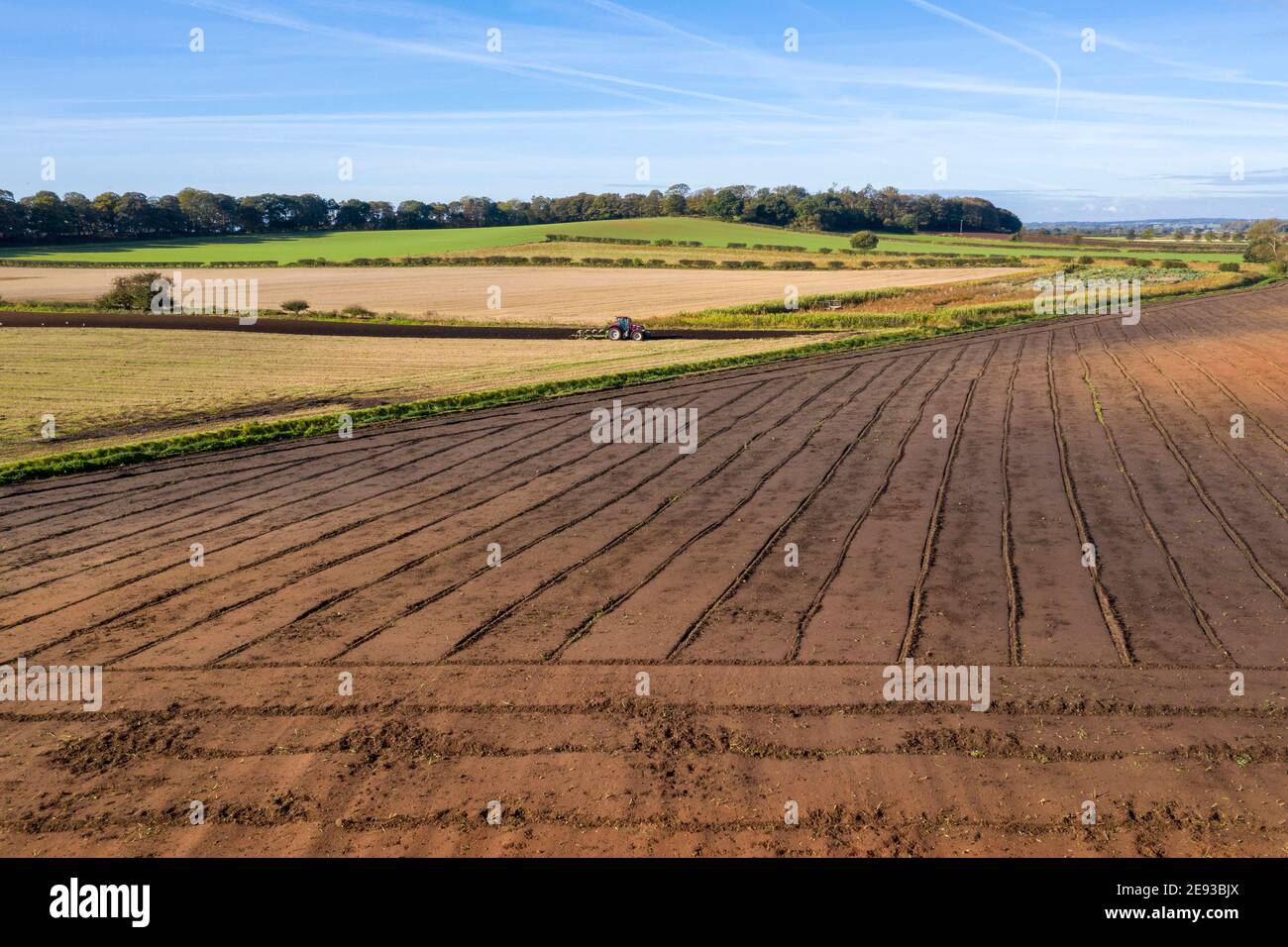 Erhöhte Ansicht des roten Traktors pflügen ein Feld mit vorbereitet Feld im Vordergrund Stockfoto