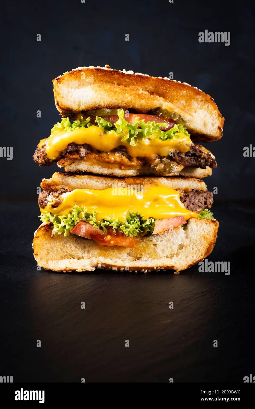 Juicy Doppel Decker Cheeseburger auf einem schwarzen Skipper Platte schwarzen Hintergrund angeordnet, Text freien Raum Stockfoto