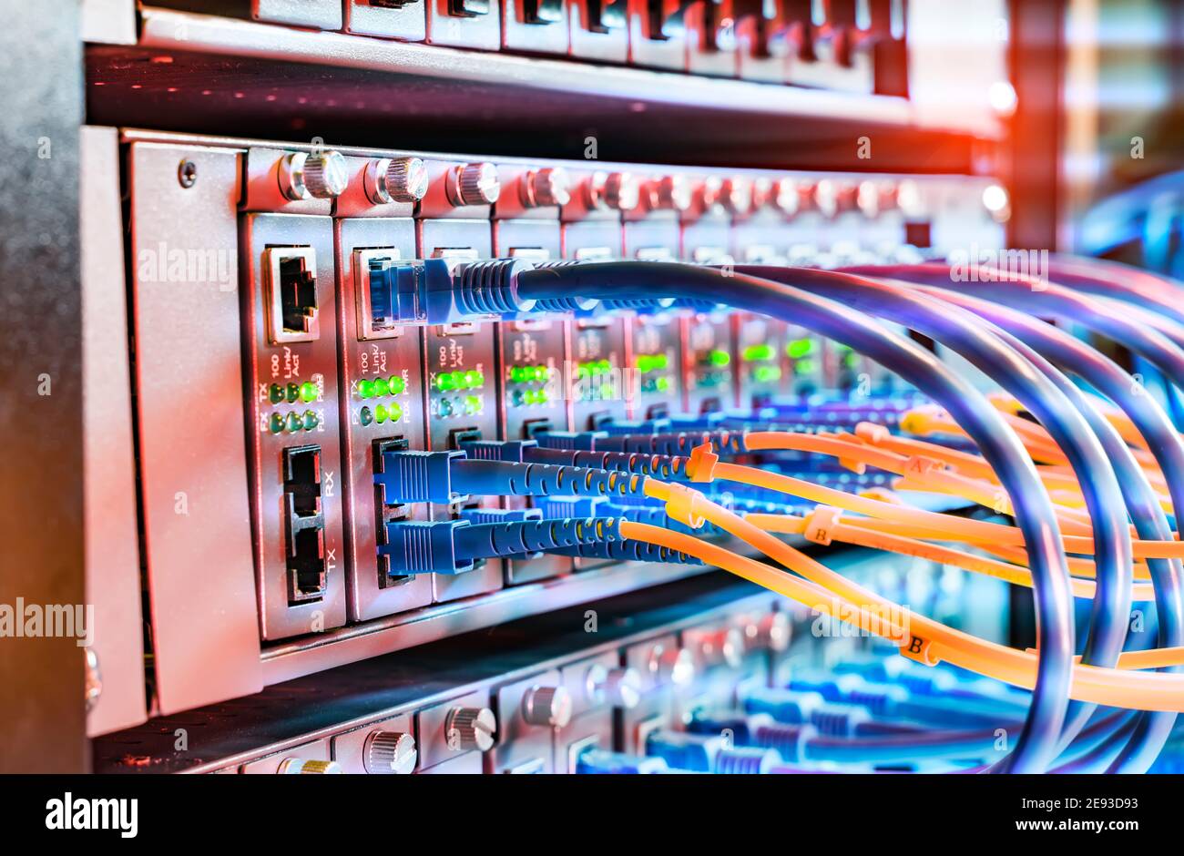 Glasfaserkabel, die an einen optischen Port und ein Netzwerk angeschlossen sind Kabel, die an ethernet-Ports angeschlossen sind Stockfoto