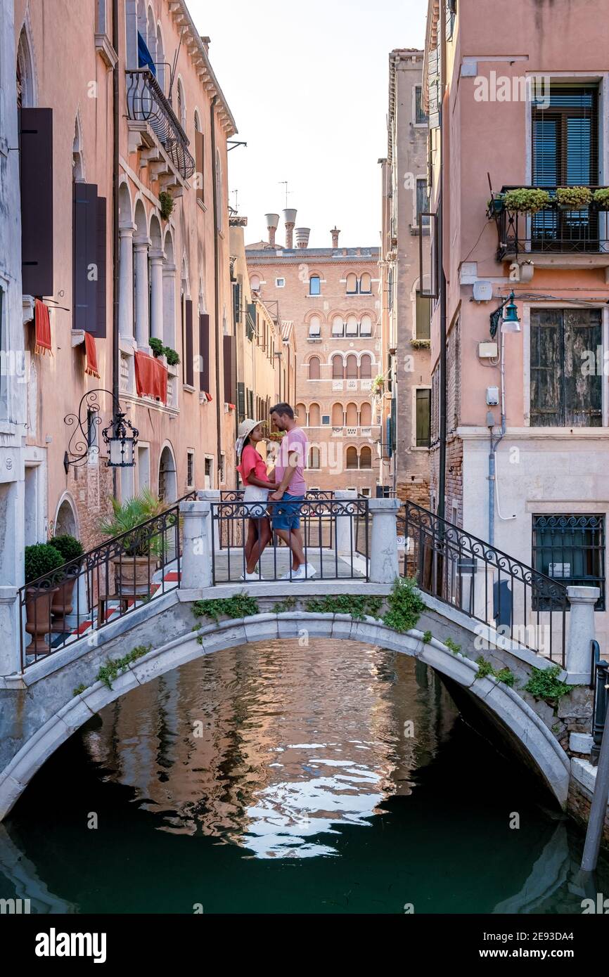 Kanäle von Venedig Italien im Sommer in Europa,Architektur und Wahrzeichen von Venedig. Italien Europa, Paar mittleren Alters Männer und Frauen im Urlaub in Venedig entspannt sitzen auf Brücke über den Kanal Stockfoto