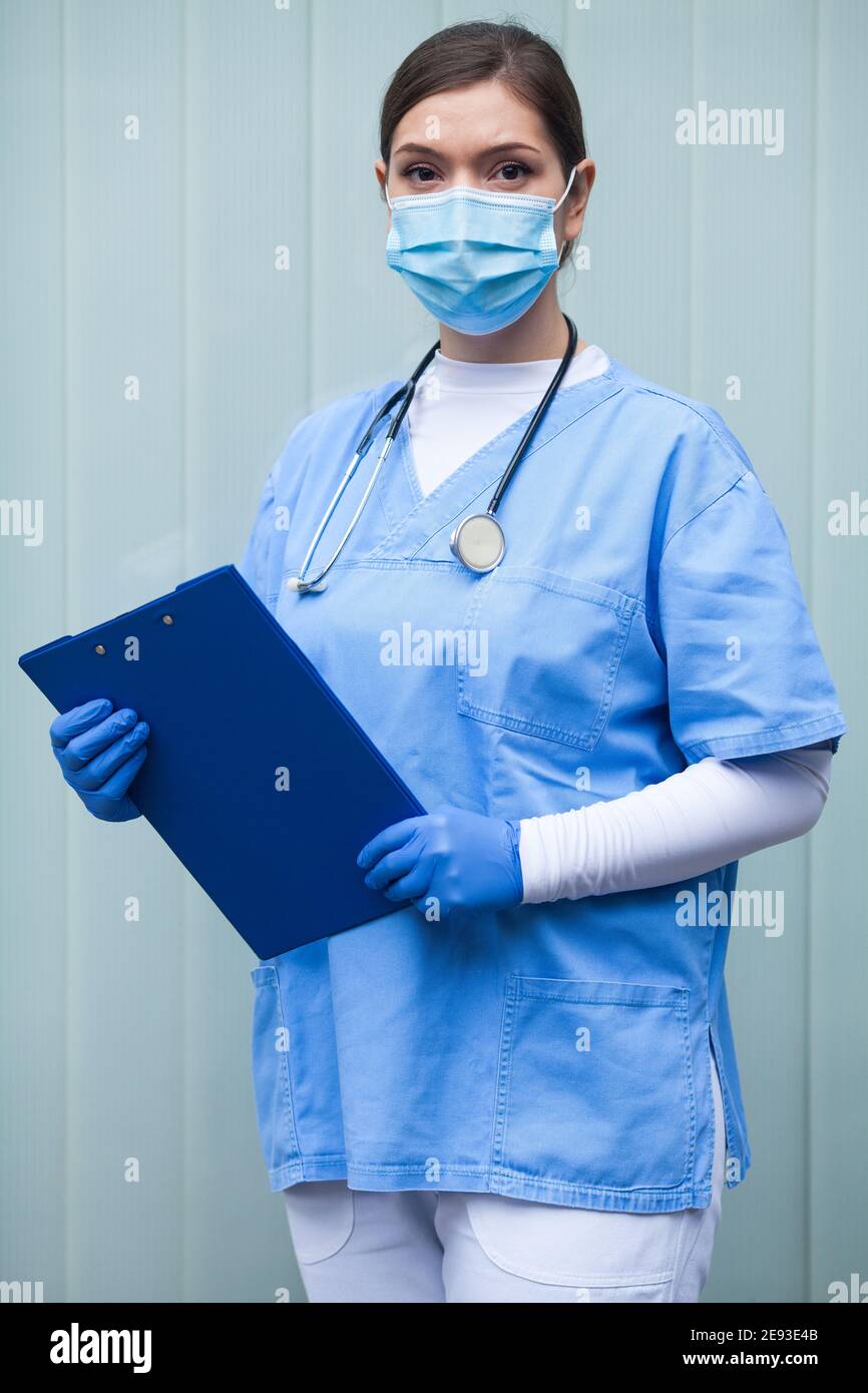 EMS UK Sanitäter Frau trägt persönliche Schutzausrüstung PSA halten Klemmbrett, vor dem Krankenhaus der Intensivstation stehend, neuartiges Coronavirus-Pandem Stockfoto