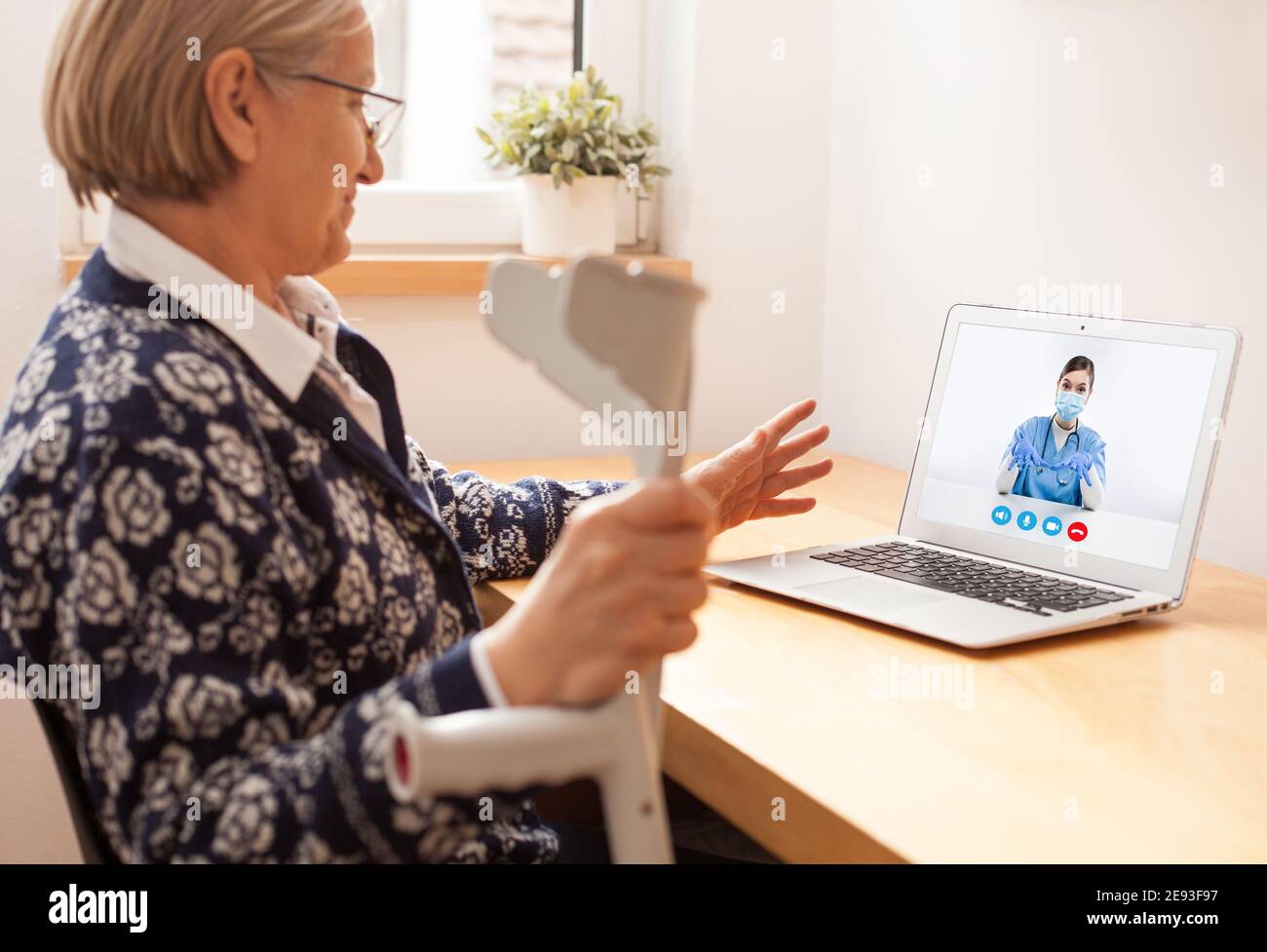 Rentner ältere Frau im Gespräch mit GP Ärztin über Virtuelle telemedizinische Videoanruf,Behandlung und Therapie von gebrochenem Bein oder Fußbruch, Soci Stockfoto