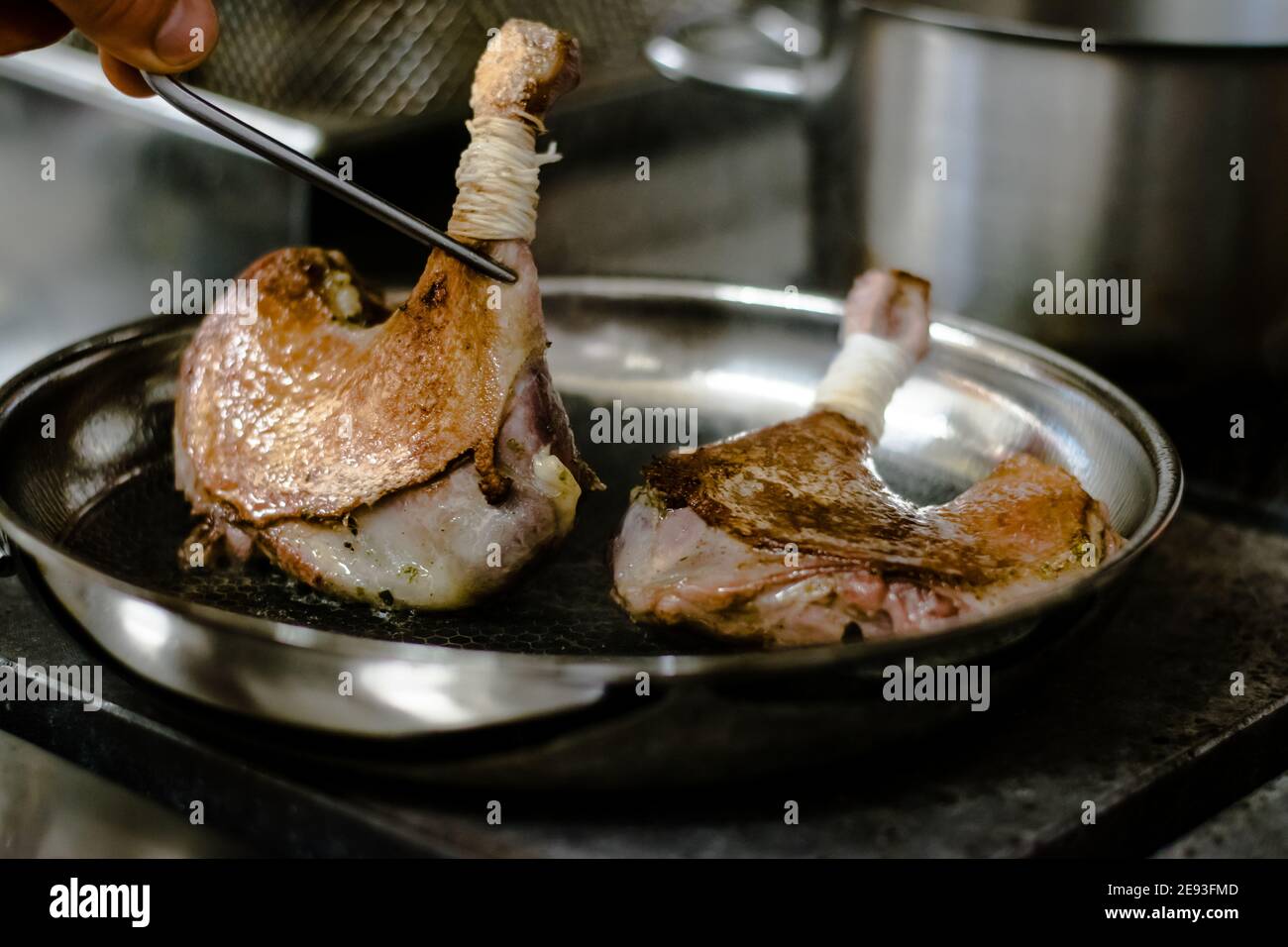 Koch bereitet Wachteln in einer Pfanne in einem Restaurant zu Stockfoto