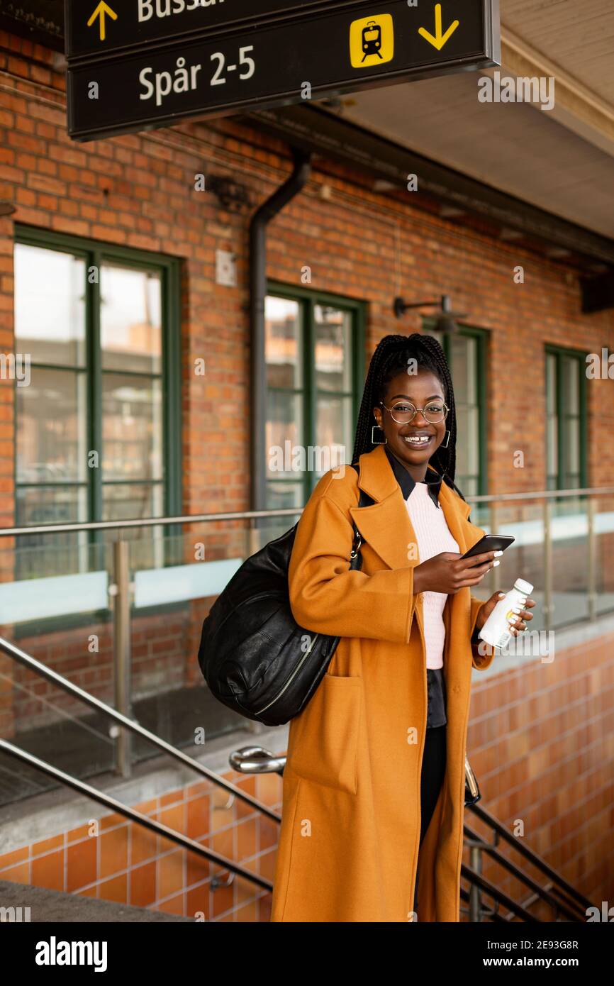 Lächelnde Frau am Bahnhof Stockfoto