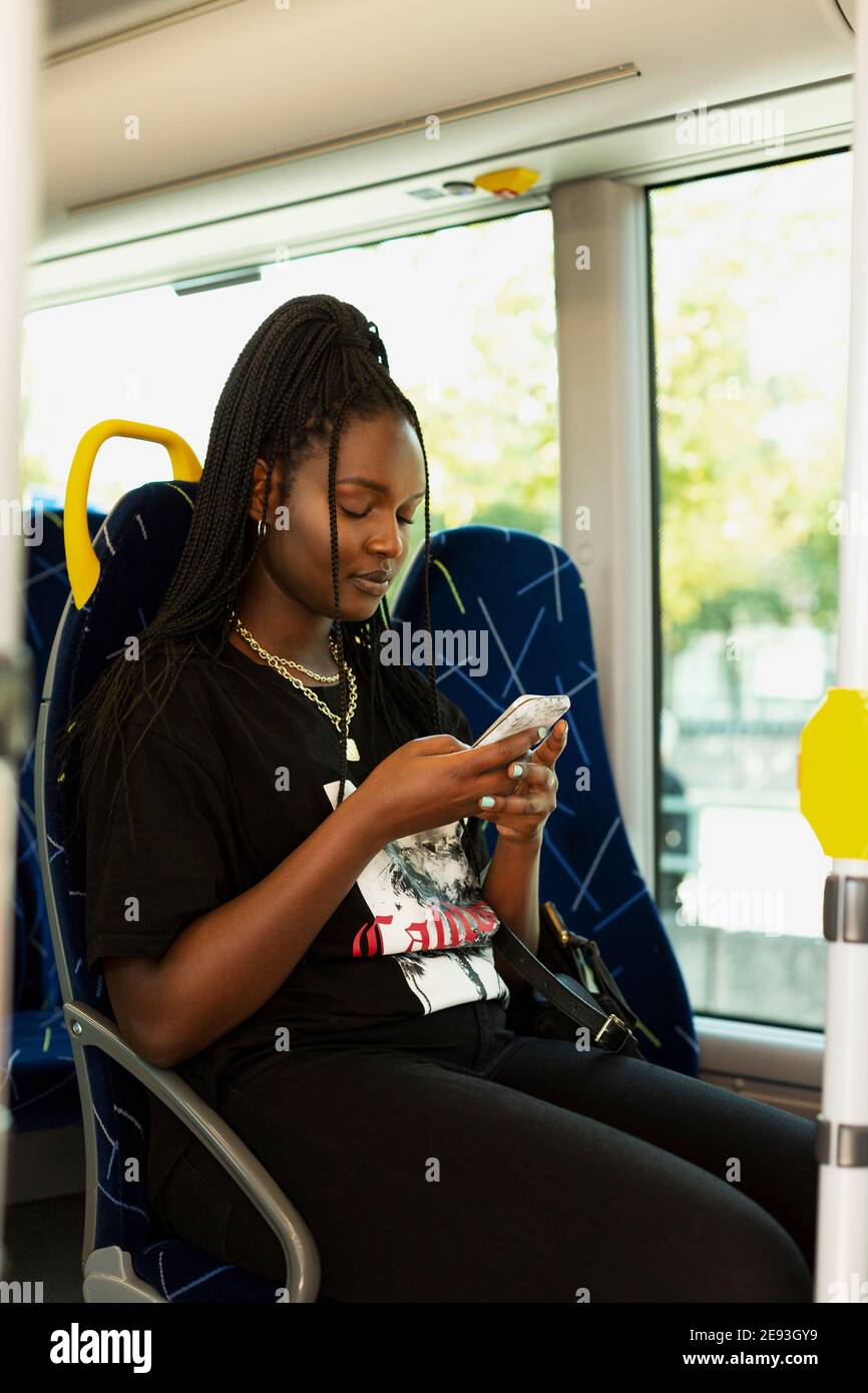 Junge Frau mit Handy im Bus Stockfoto
