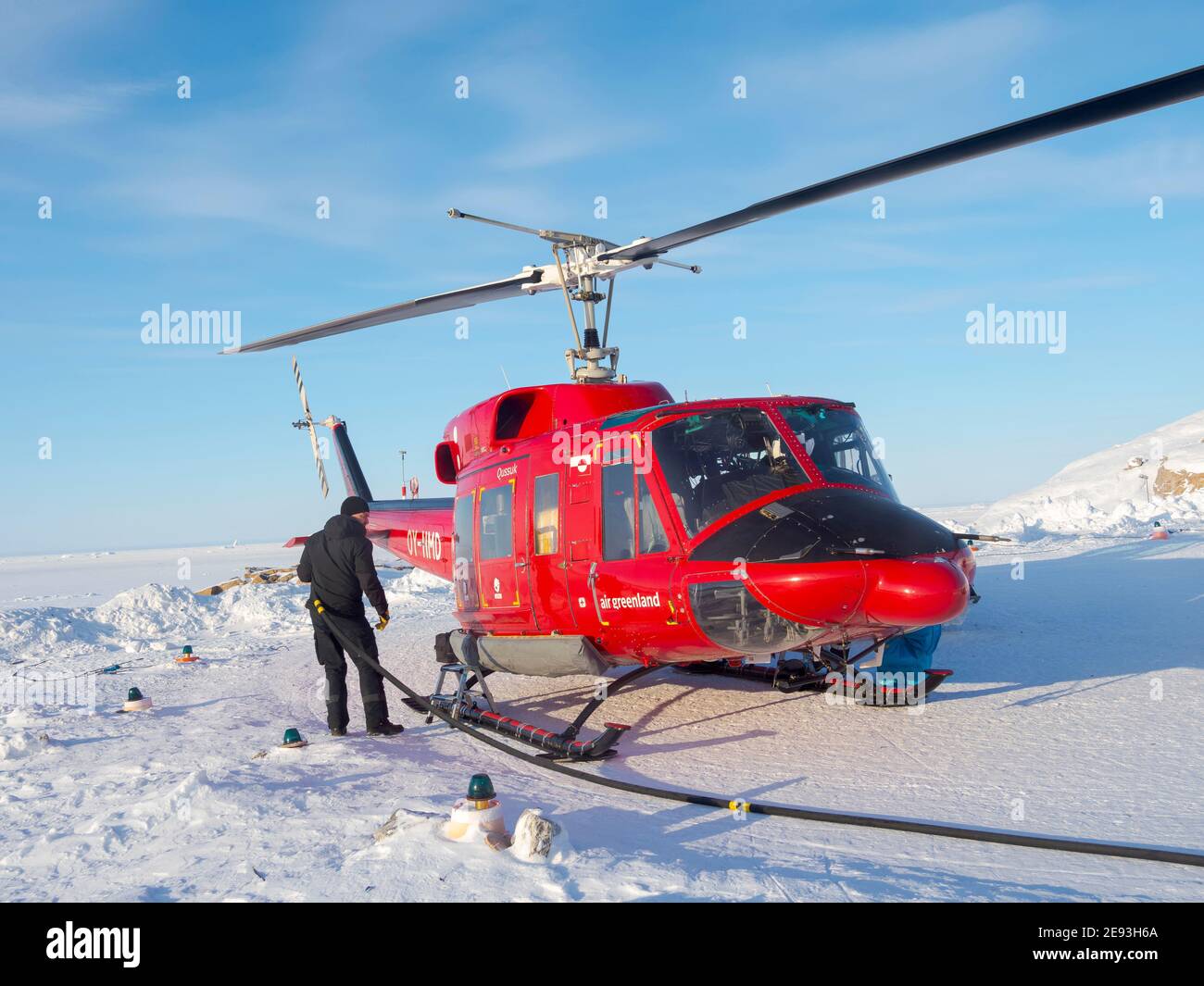 Piloten tanken den Hubschrauber auf dem Hubschrauberlandeplatz. Im Winter ist der Hubschrauber die einzige Verbindung zum Rest Grönlands. Das traditionelle Dorf Ku Stockfoto