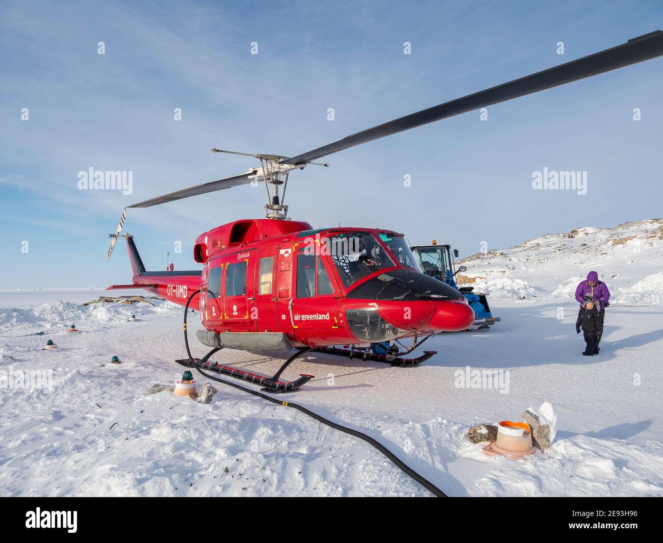 Piloten tanken den Hubschrauber auf dem Hubschrauberlandeplatz. Im Winter ist der Hubschrauber die einzige Verbindung zum Rest Grönlands. Das traditionelle Dorf Ku Stockfoto