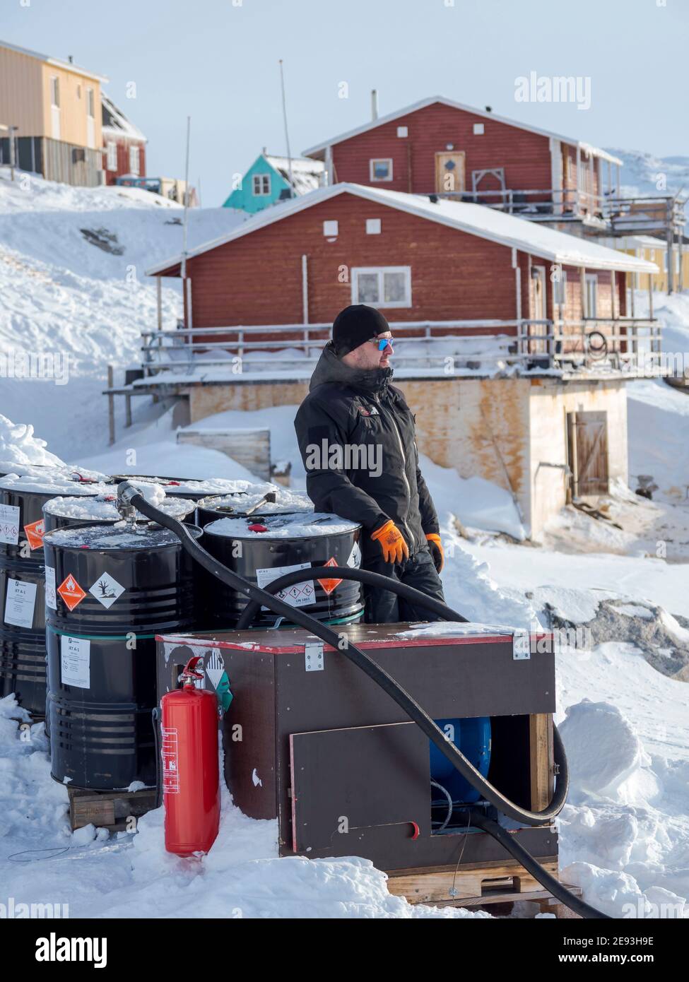 Piloten tanken den Hubschrauber auf dem Hubschrauberlandeplatz. Im Winter ist der Hubschrauber die einzige Verbindung zum Rest Grönlands. Das traditionelle Dorf Ku Stockfoto