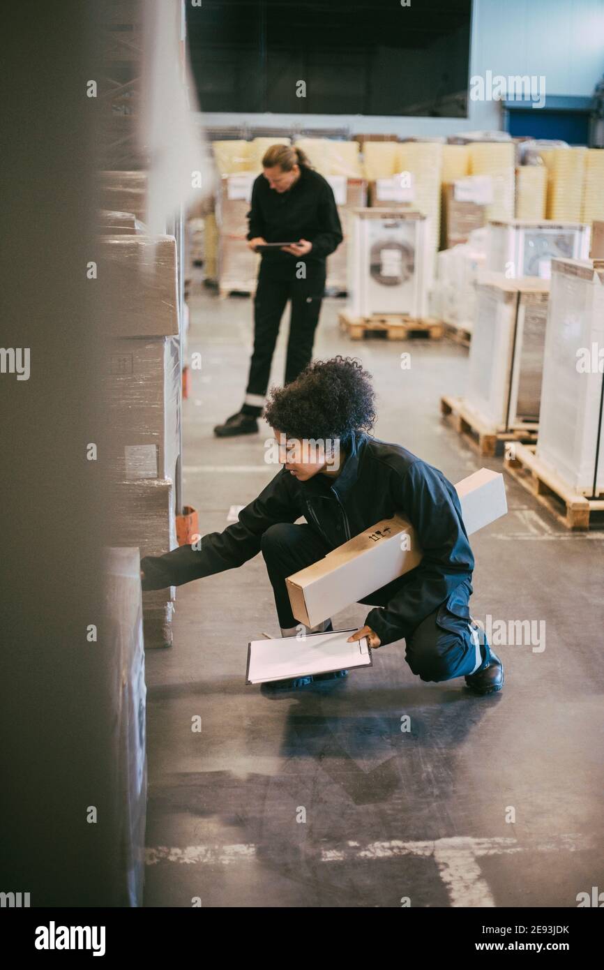 Weibliche manuelle Arbeiter untersuchen die Behälter im Verteilungslager Stockfoto