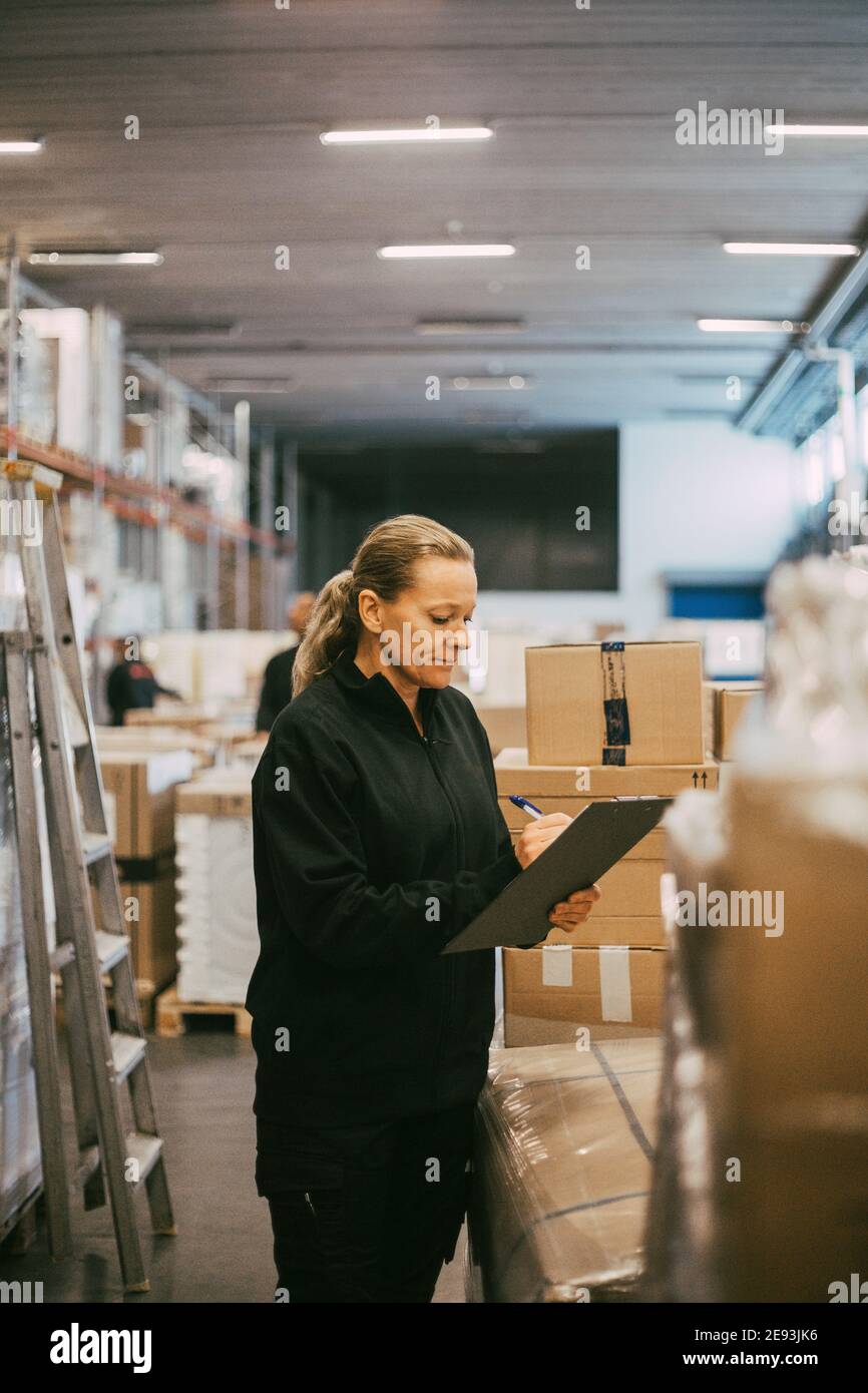Reife manuelle Arbeiterin, die Pakete im Logistiklager analysiert Stockfoto