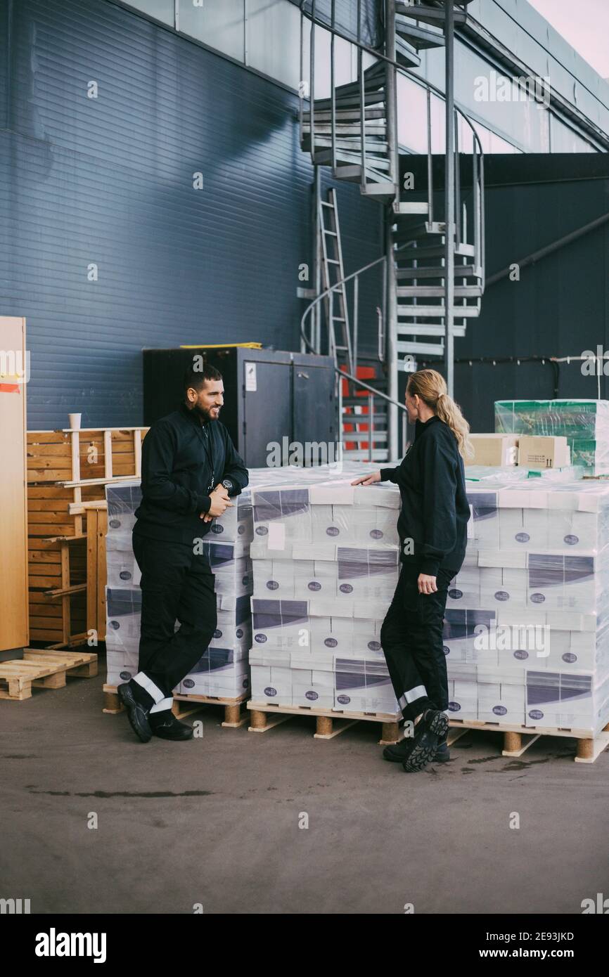 Weibliche und männliche professionelle Stehen bei Paketen im Lager Stockfoto