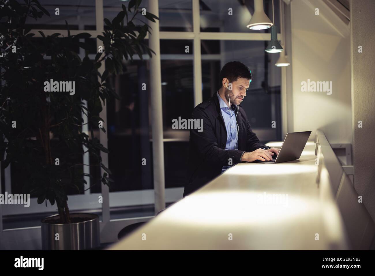 Mann, der im öffentlichen Raum mit einem Laptop arbeitet Stockfoto