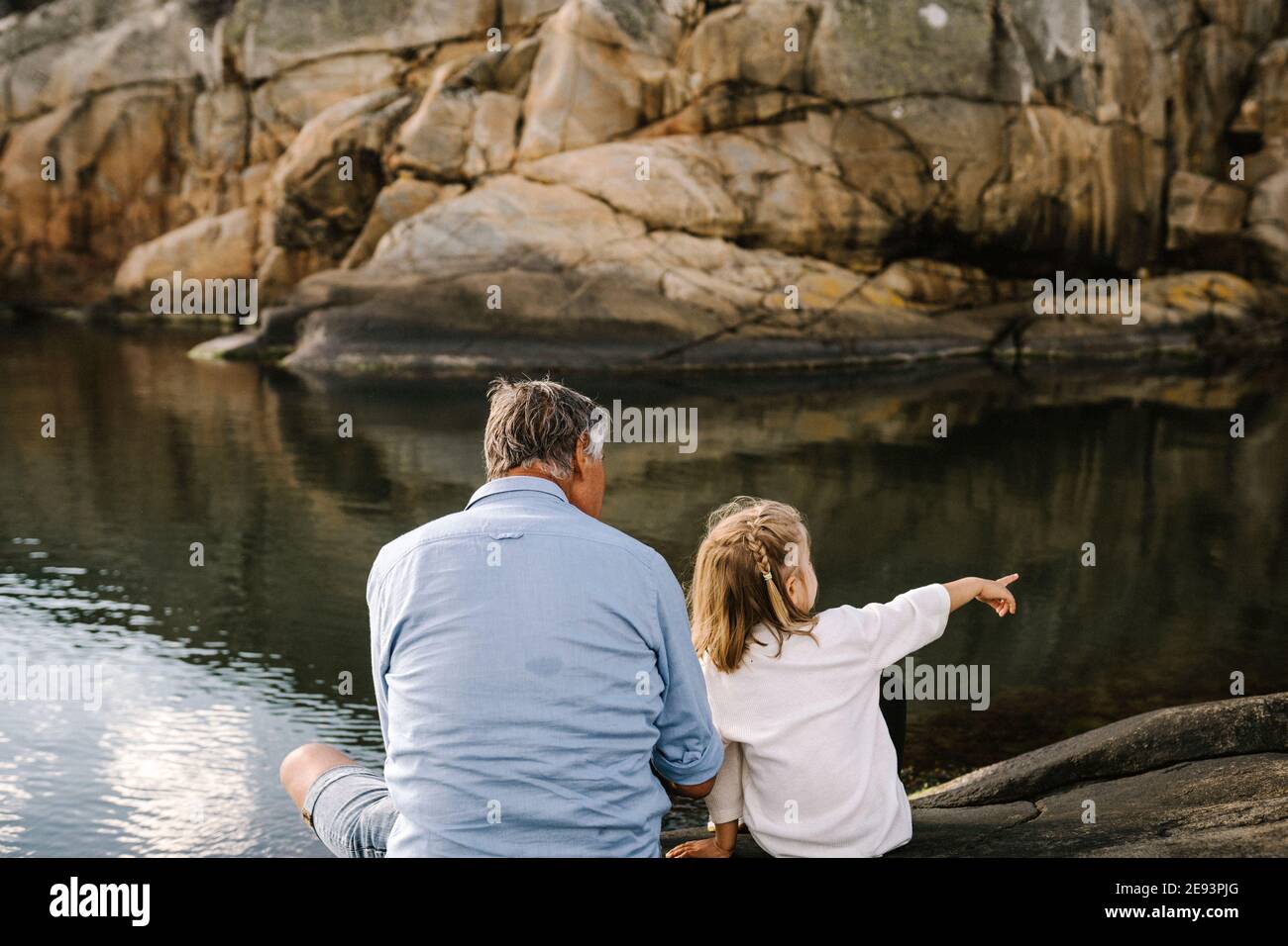 Vater und Tochter sitzen auf See Stockfoto