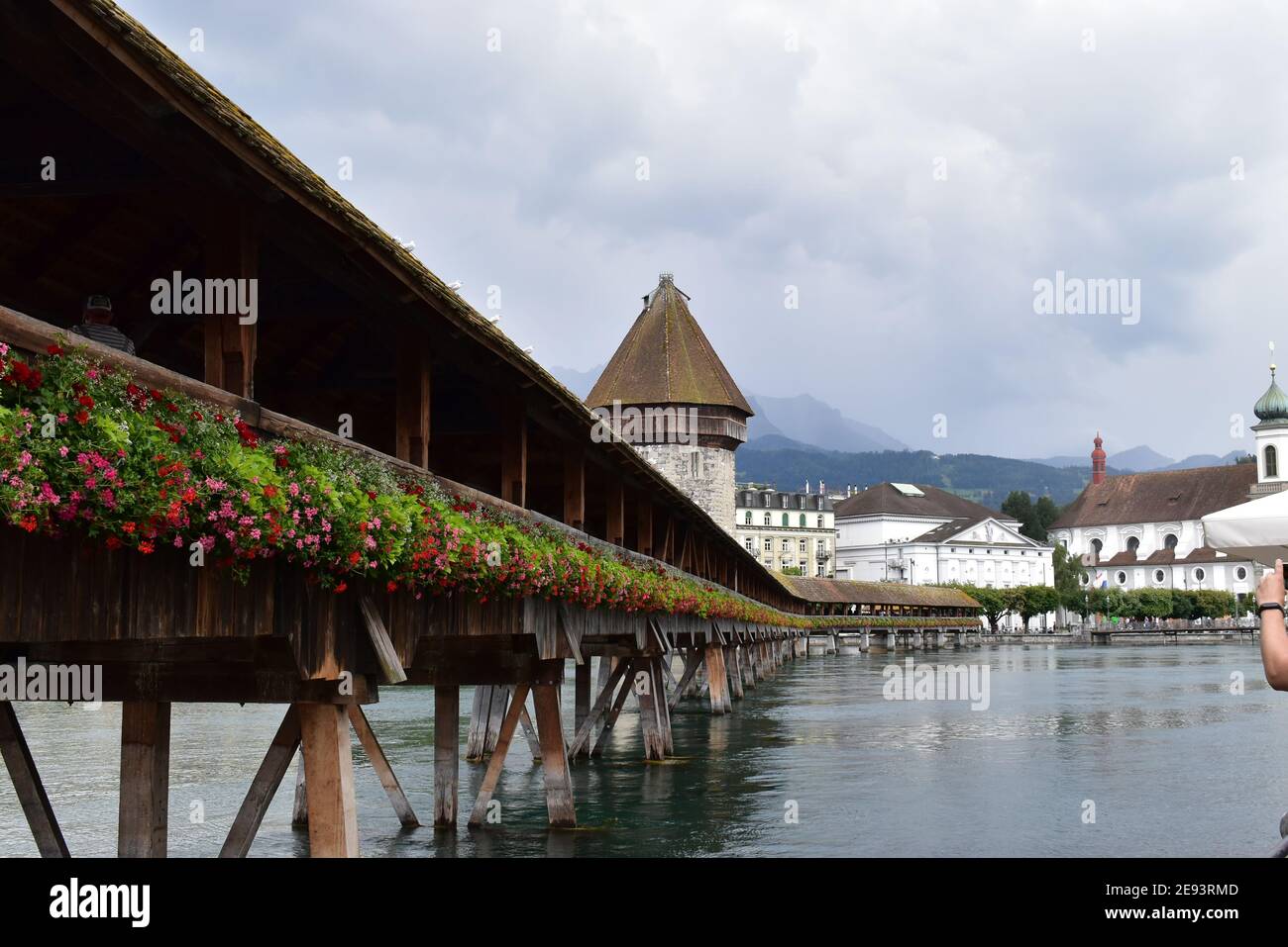 Ein ruhiger schweizer Sommertag: Ein Tagesausflug zur Kapellbrücke in Luzern. Die Blumen erzeugen einen schönen Kontrast zu der Holzbrücke und dem grauen See Stockfoto