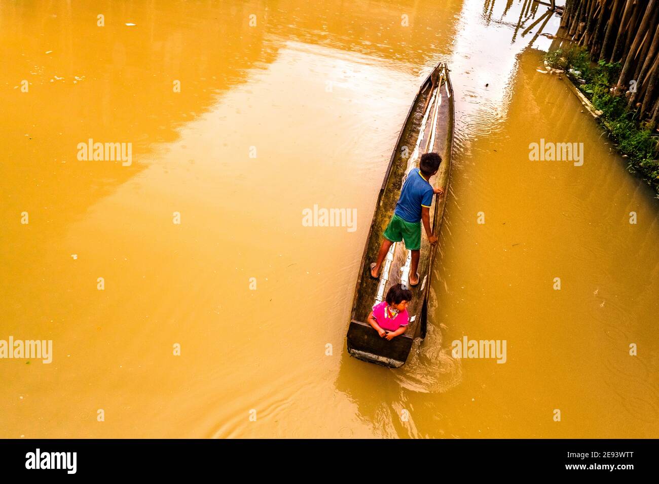 Die indigenen Kinder, die zum Stamm der Emberá-Wounaan gehören, fahren mit einem Kanu auf dem schlammigen Wasser des Flusses Atrato in Quibdó, Kolumbien. Stockfoto