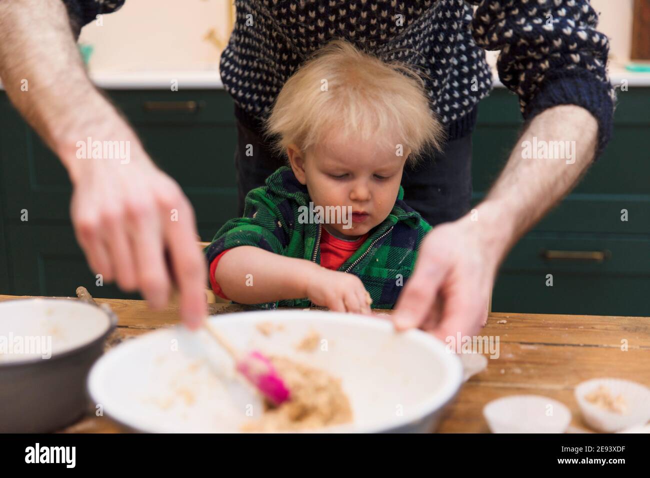 Ein junges Kleinkind mit Spaß hilft seinem Vater Kuchen in der Küche backen.. Stockfoto