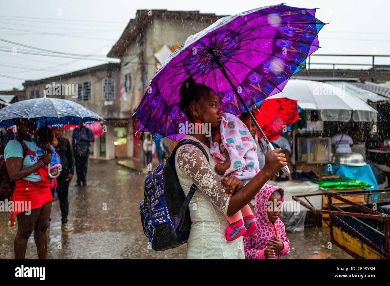 Eine junge afro-kolumbianische Frau, die ihr Baby trägt, geht auf einem Straßenmarkt entlang des Flusses Atrato in Quibdó, Chocó, der pazifischen Region Kolumbiens. Stockfoto