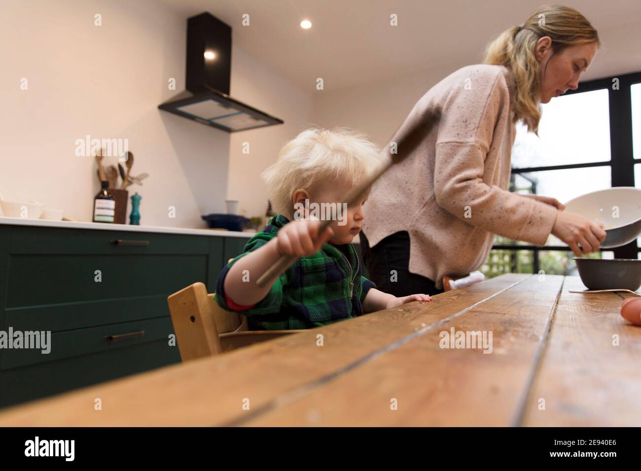 Ein Kleinkind hilft, einen Kuchen mit einem großen Spatel zu backen. Stockfoto