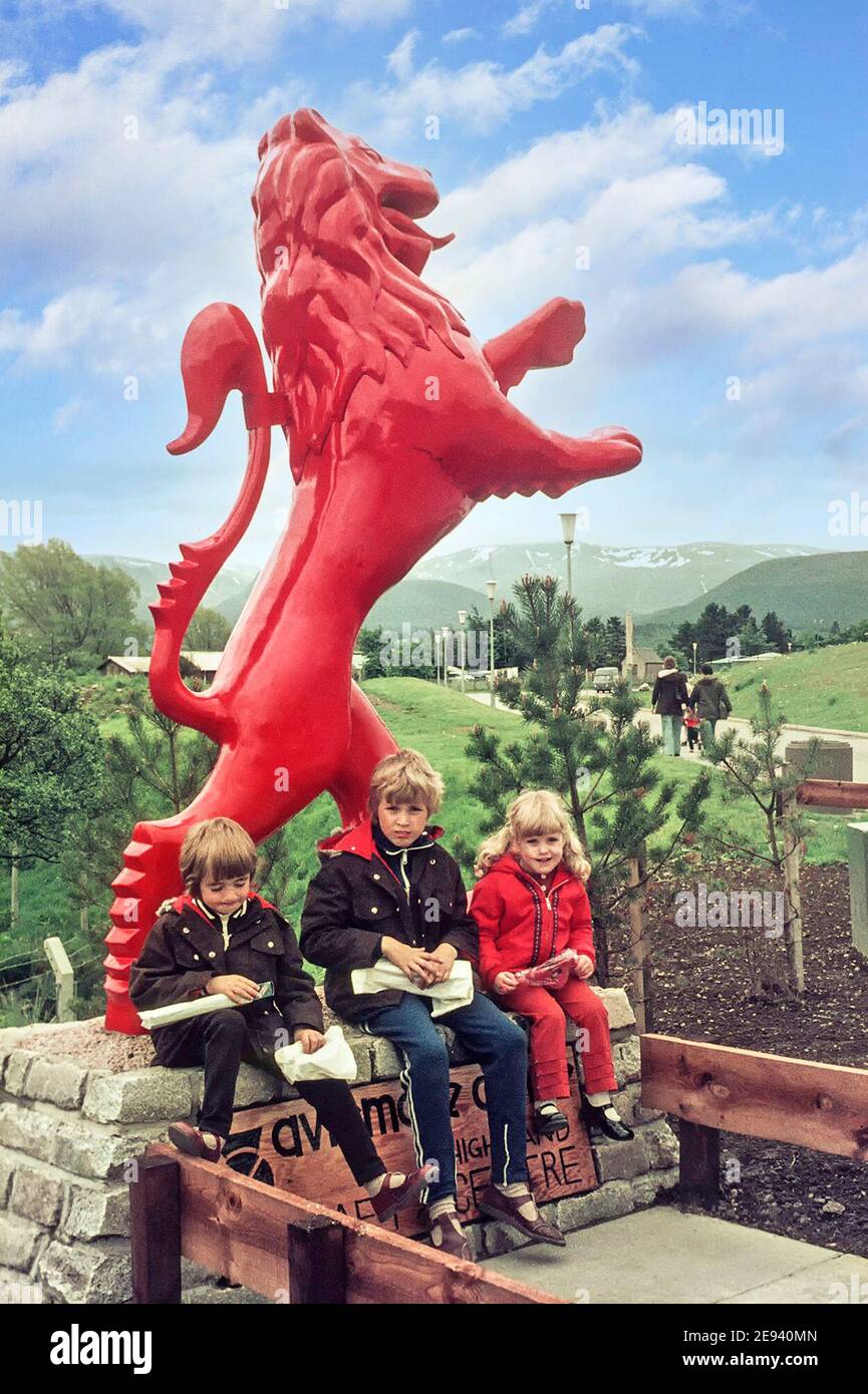 Familie Touring Urlaub drei Kinder zwei Jungen ein Mädchen essen Fish and Chips Mittagspause im Freien sitzen vor Rote schottische Löwenstatue Archiv 1970s Aviemore Schottische Highlands Großbritannien Stockfoto