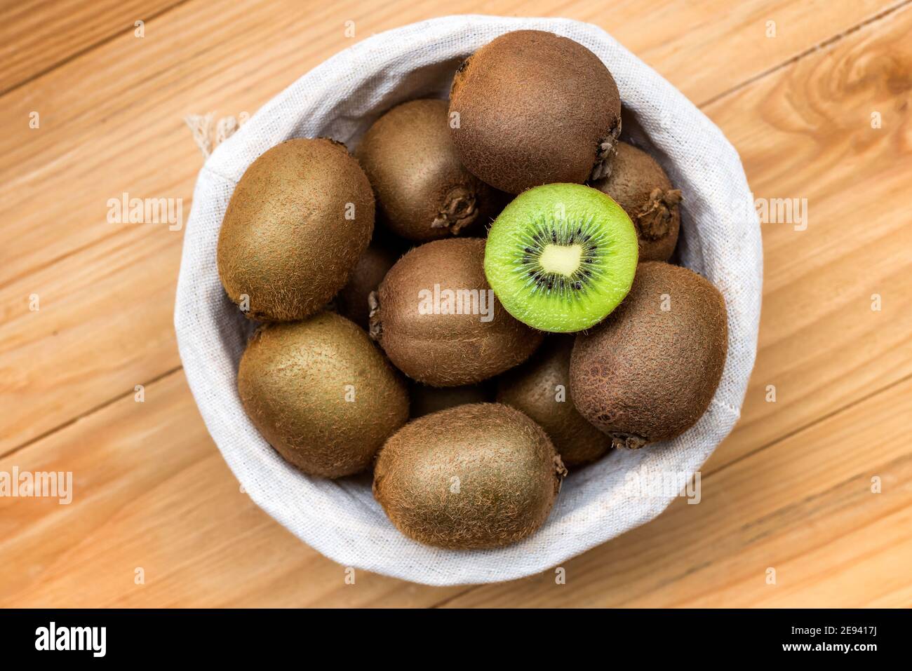 Frische Kiwi-Früchte in einem Korbwickler auf Holzhintergrund Stockfoto