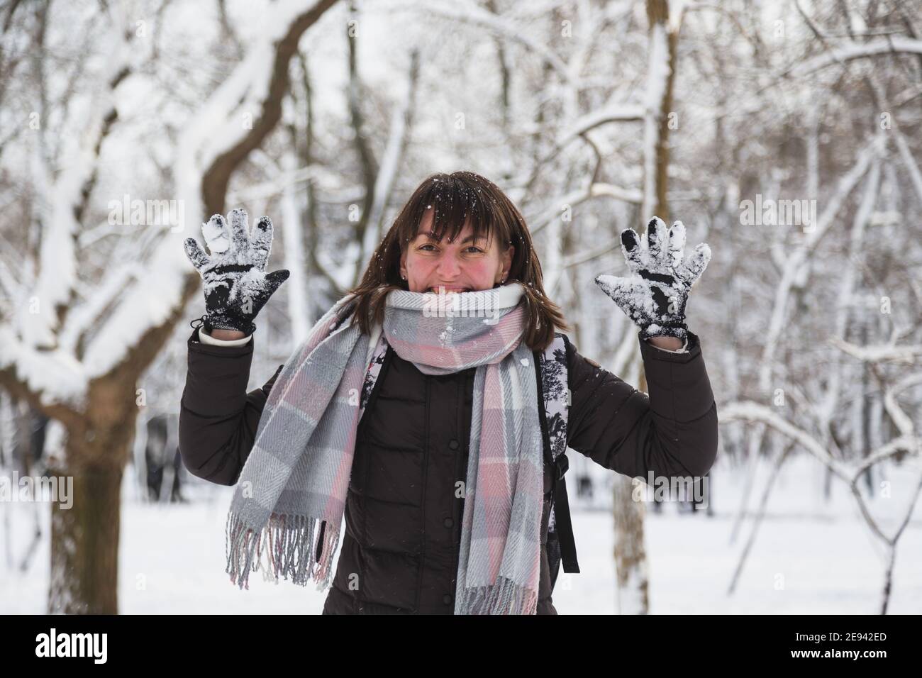 Glückliche junge Frau nach dem Spielen mit Schnee in einem schneebedeckten Winter Park. Mädchen genießen verschneiten Winter, frostigen Tag. Spaziergang im Winterwald Stockfoto