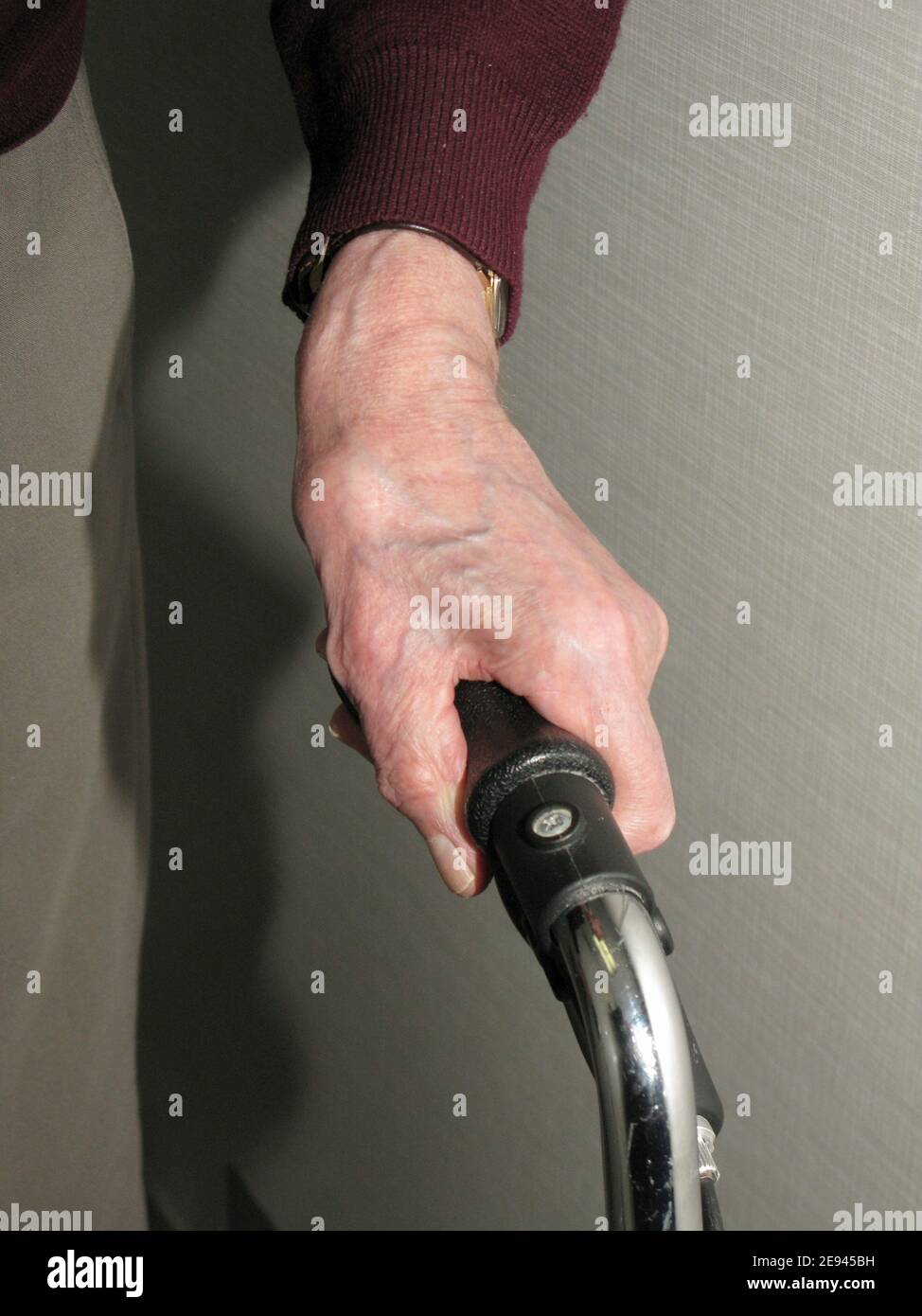 Nahaufnahme der Hand eines Senior, der an hält An den Griff eines Laufers auf Rädern Stockfoto