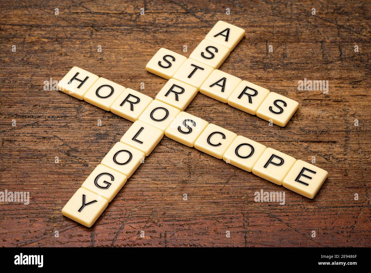 Astrologie, Sterne und Horoskop Kreuzworträtsel in Elfenbein Buchstaben Fliesen gegen rustikal verwitterten Holz Stockfoto