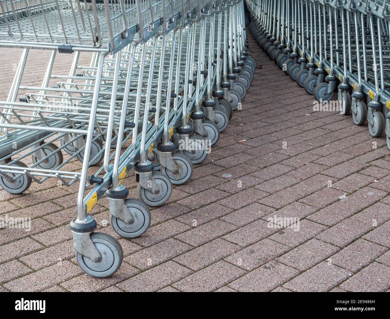 Viele Metall-Einkaufswagen auf einem Parkplatz in der Nähe von Supermarkt im Freien. Stockfoto