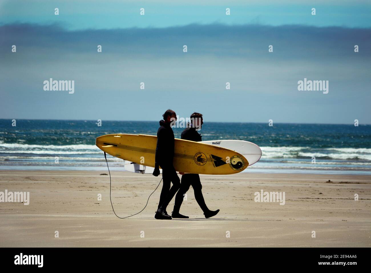 Zwei Männer laufen am Strand entlang mit ihren Surfbrettern an der Pazifikküste in der Nähe von Newport, Oregon. Stockfoto