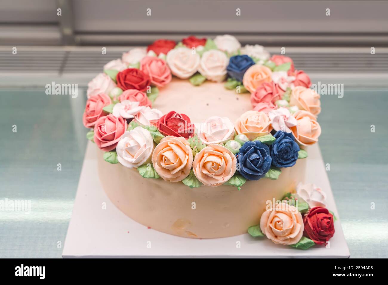 Schöne hausgemachte Kuchen in Form eines Einhorns mit Cremefarbene Blumen auf dem Tisch Stockfoto